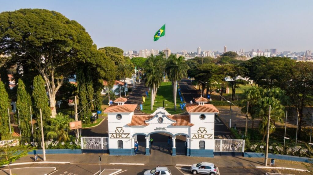 Entrada principal do Parque Fernando Costa, sede da ABCZ em Uberaba (MG), onde acontece a Expogenética 2025, com destaque para a bandeira do Brasil ao fundo.